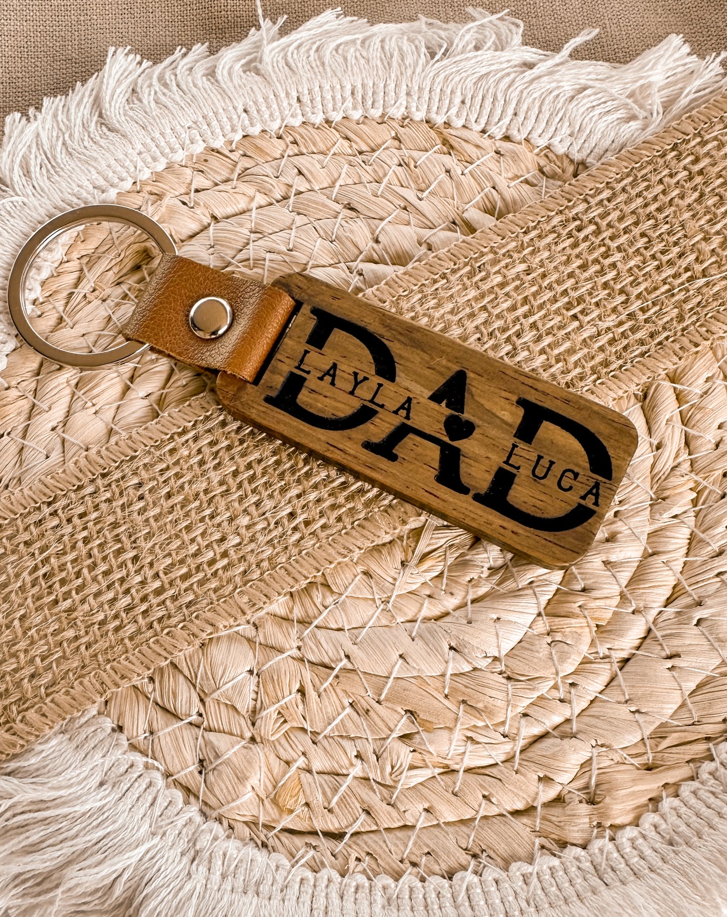 Two leather keychains with custom engraved text on a textured wooden surface, personalised key ring, gift for dad