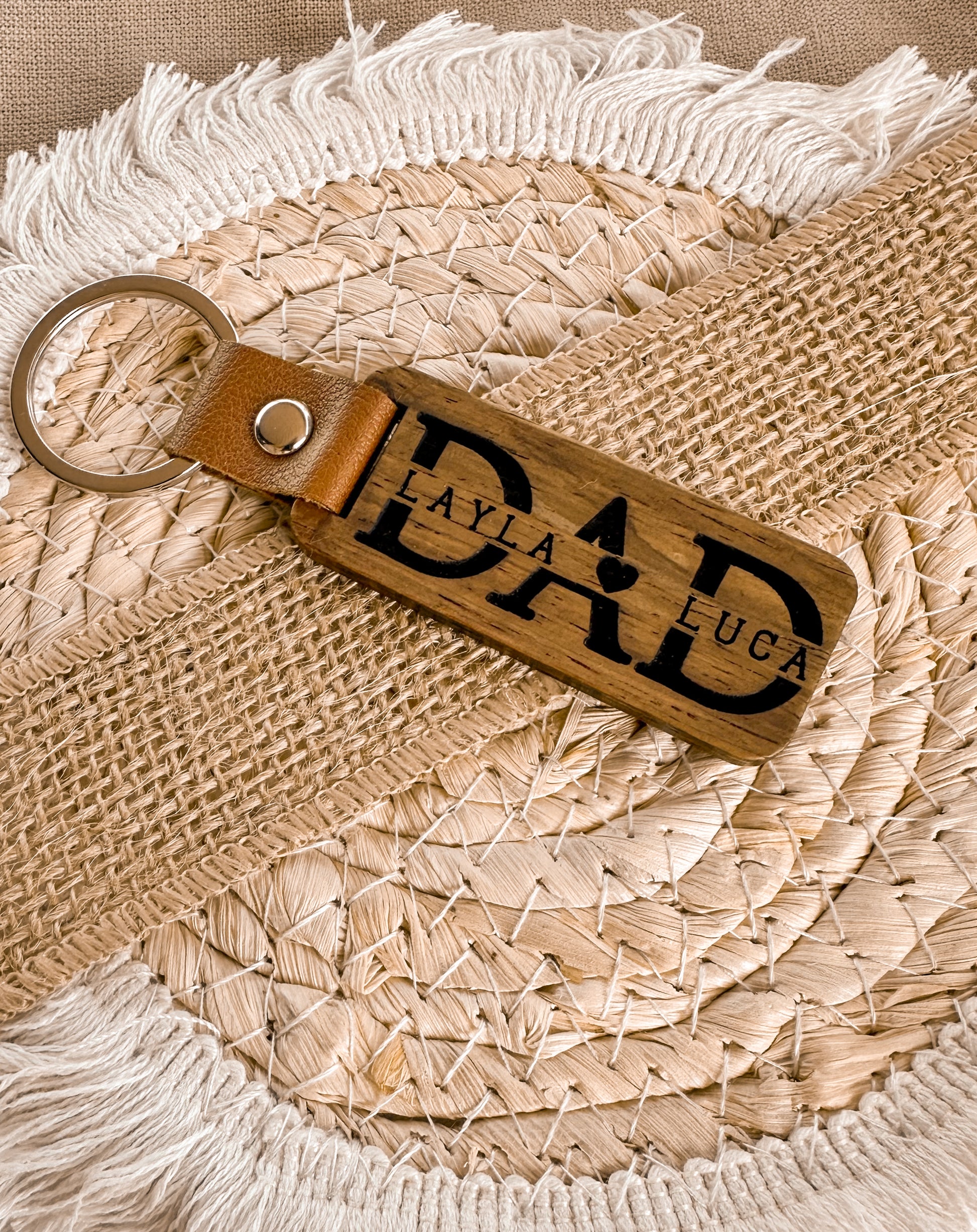 Two leather keychains with custom engraved text on a textured wooden surface, personalised key ring, gift for dad