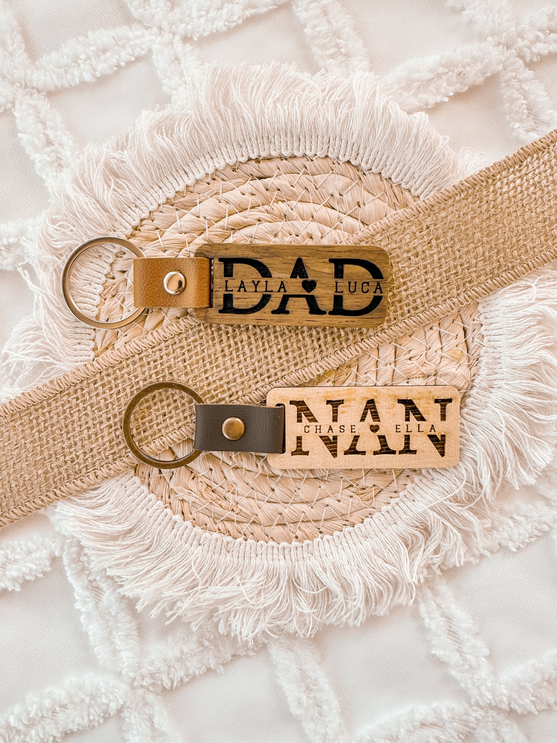 Two leather keychains with custom engraved text on a textured wooden surface, personalised key ring, gift for dad