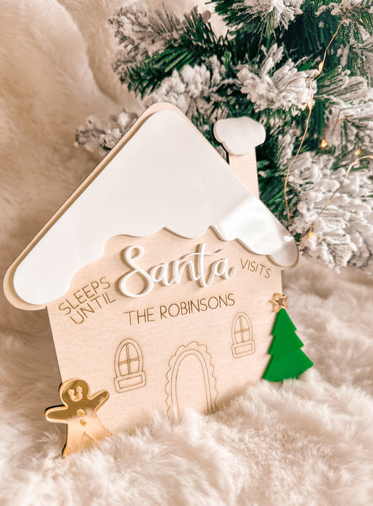 Decorative gingerbread house christmas countdown sign with 'Sleeps Until Santa Visits' text, Christmas tree in the background, wood and acrylic
