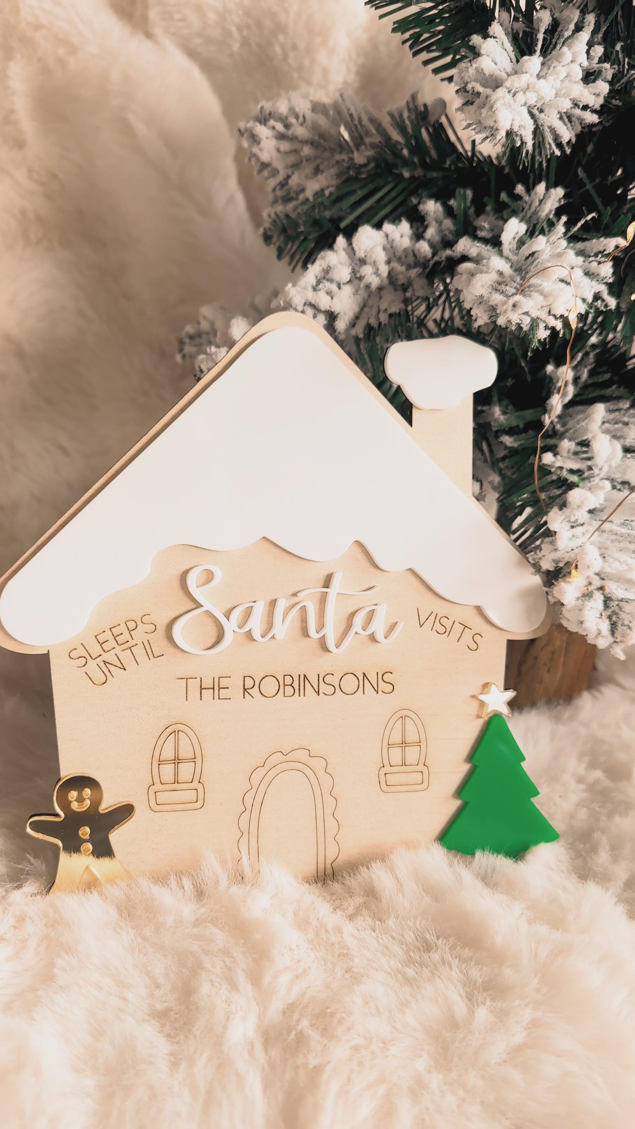Decorative gingerbread house christmas countdown sign with 'Sleeps Until Santa Visits' text, Christmas tree in the background, wood and acrylic